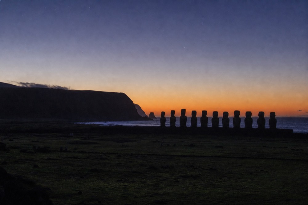 Empty dawn light over the ahu at Tongariki with the silhouettes of moai backs against a pale orange horizon