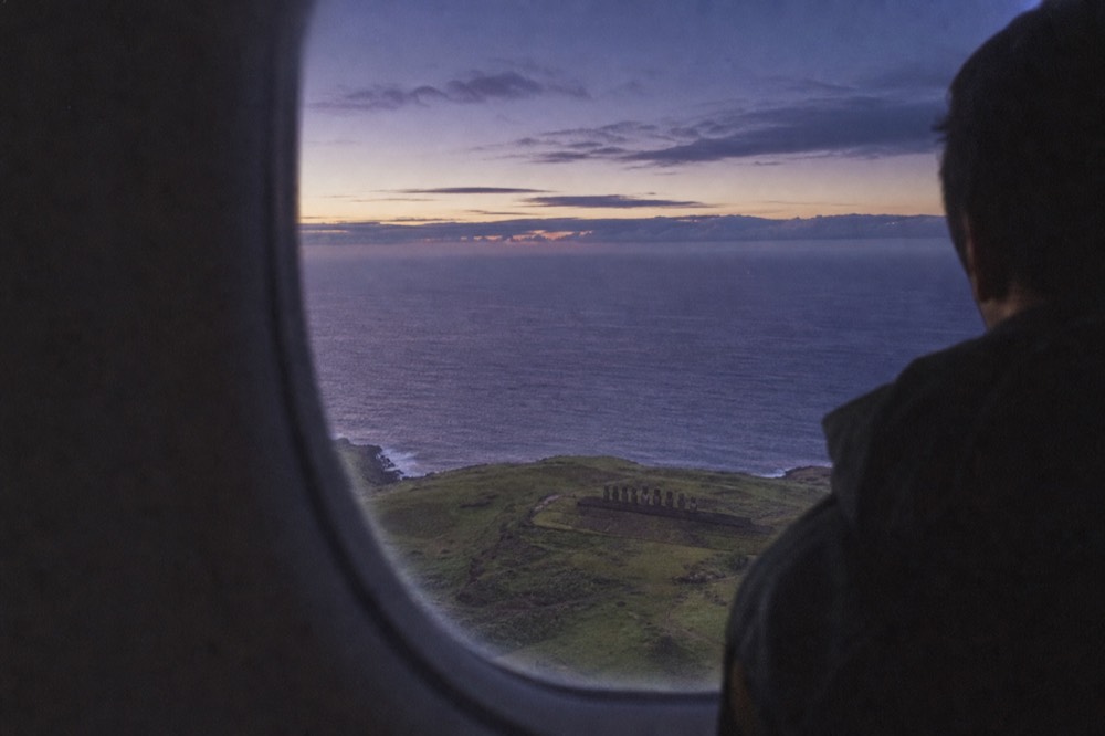 Open Pacific ocean seen through an aircraft window on the descent toward the island's green coastline
