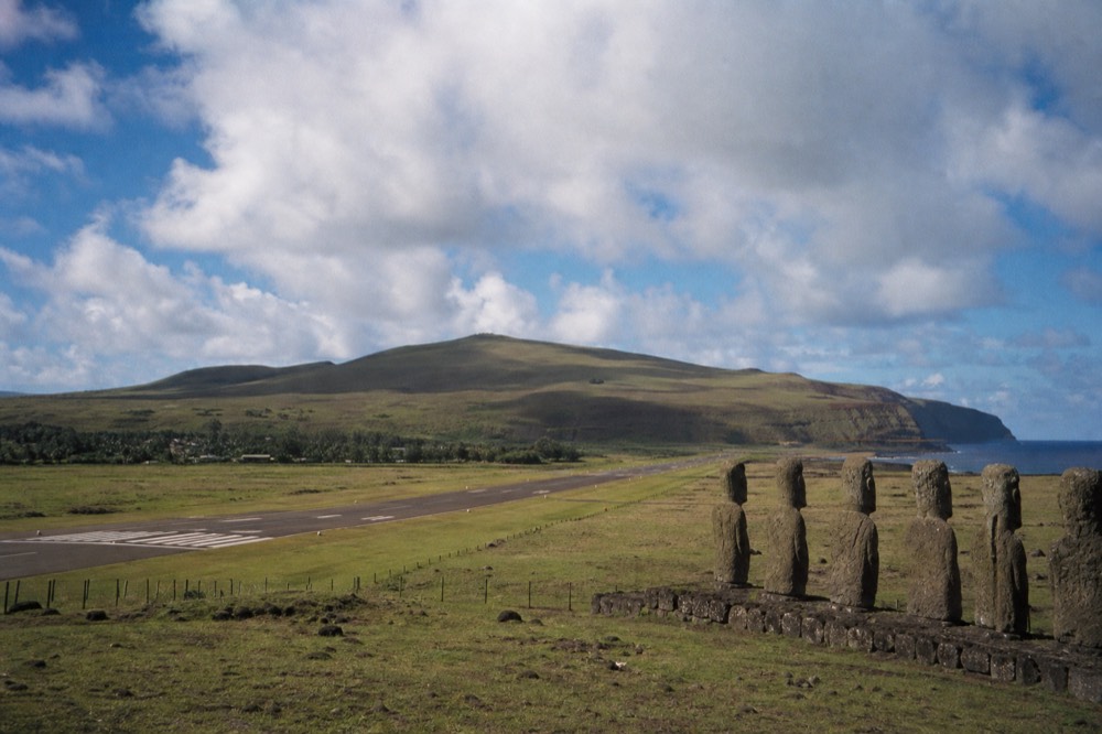 Single runway at Mataveri airport running toward green volcanic hills with the Pacific behind