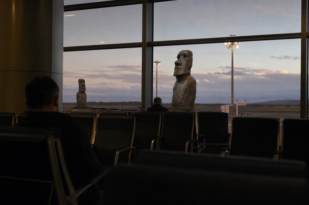 Departure board glow and empty seats at a Santiago boarding gate before an early morning long-haul flight