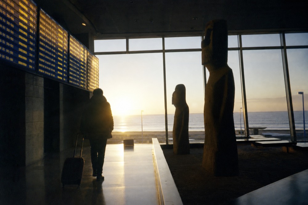 Departure board glow reflected on a polished terminal floor at Santiago airport in the early morning