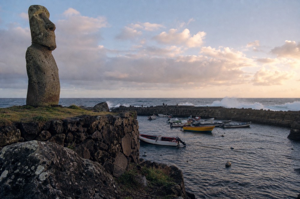Small fishing boats moored inside the sheltered harbour wall at Hanga Roa with swell breaking outside