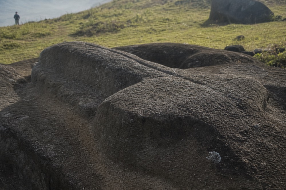 Close view of chisel-marked volcanic tuff on an unfinished moai still joined to the quarry bedrock