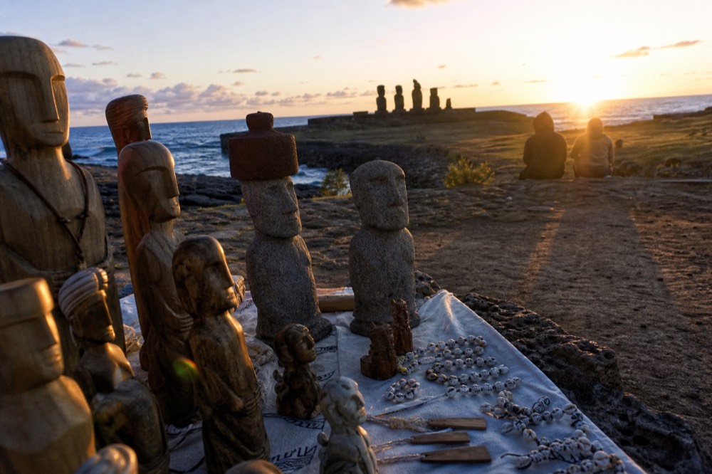 Hand-carved wooden figures and shell ornaments arranged on a cloth-covered market table in Hanga Roa