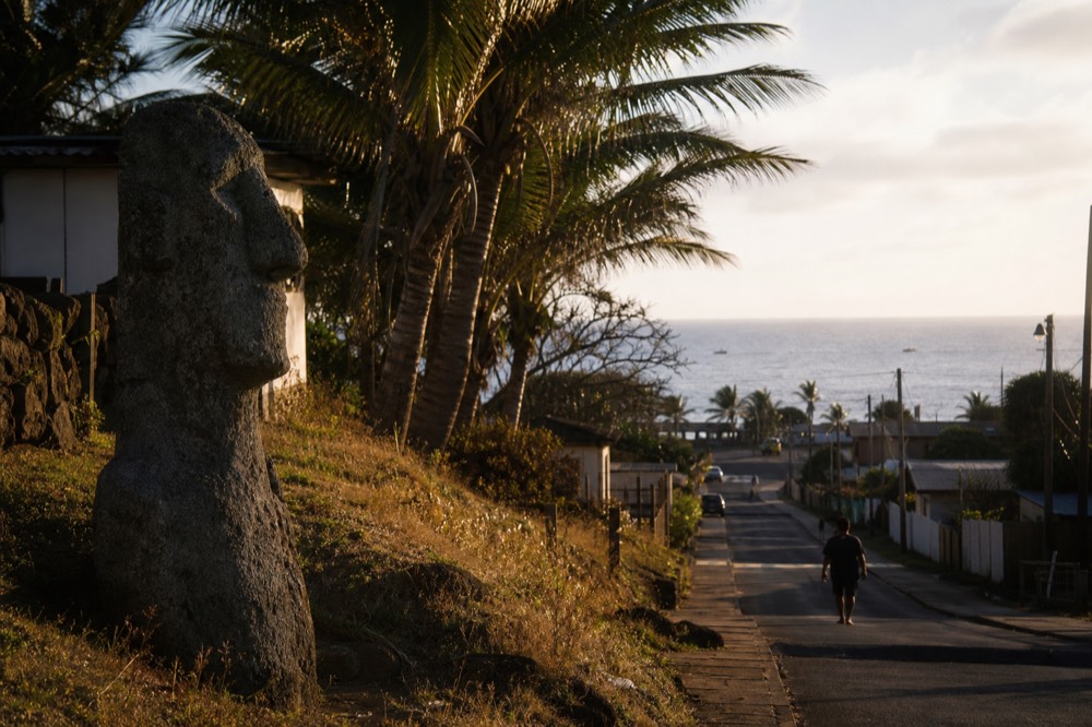 Palm-lined street of low houses running gently downhill toward the sea in the middle of Hanga Roa